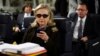 FILE - In this Oct. 18, 2011, file photo, then-Secretary of State Hillary Rodham Clinton checks her Blackberry from a desk inside a C-17 military plane upon her departure from Malta, in the Mediterranean Sea, bound for Tripoli, Libya.