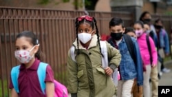 Siswa berbaris sebelum memasuki Sekolah Christa McAuliffe di Jersey City, New Jersey, 29 April 2021. Gubernur Phil Murphy akan mengakhiri mandat masker di sekolah dan pusat penitipan anak, di seluruh negara bagian New Jersey, Senin , 7 Februari 2022. (AP Photo/Seth Wenig, File)
