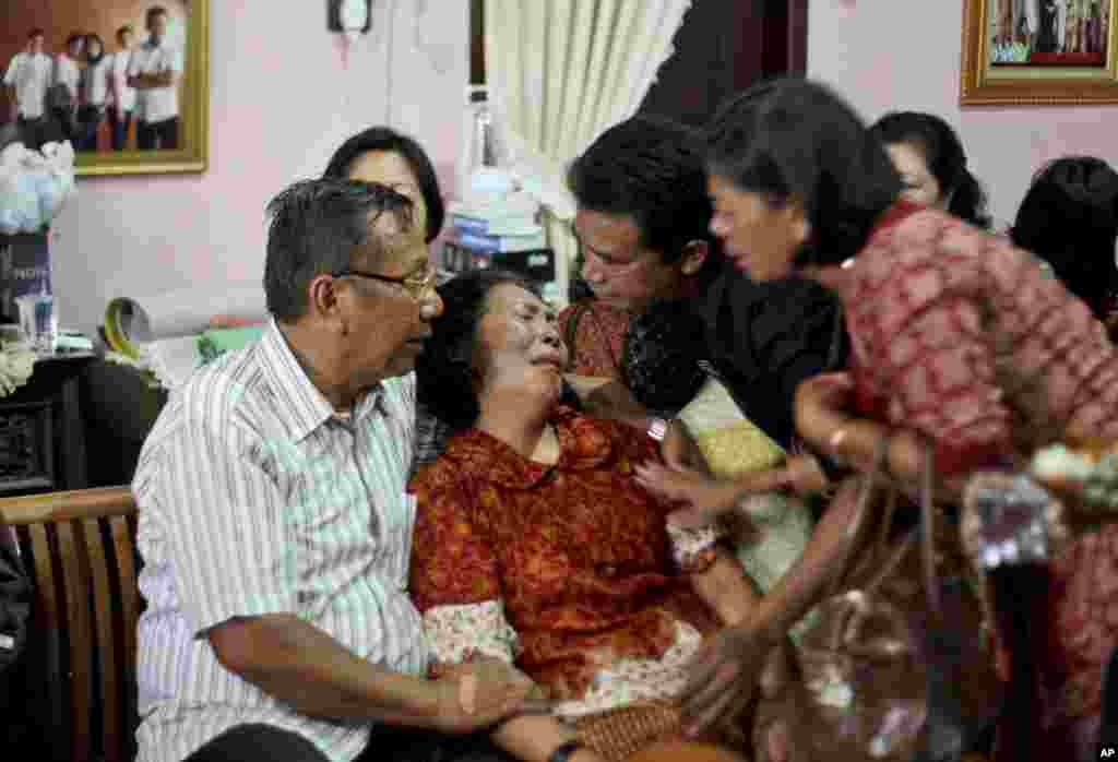 Family members comfort Chrisman Siregar, left, and his wife Herlina Panjaitan, the parents of Firman Siregar, one of the Indonesian citizens registered on the manifest of the Malaysia Airlines jetliner flight MH370 that went missing, Medan, North Sumatra, Indonesia, March 9, 2014. 