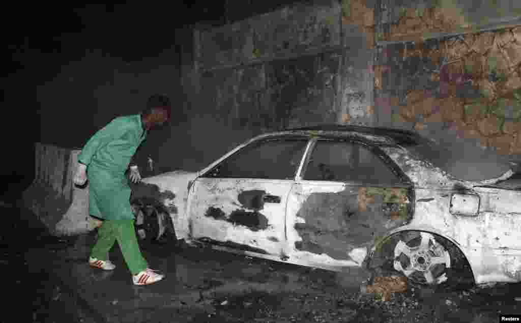A firefighter looks at a destroyed car at the scene of an explosion outside the Jazeera Hotel in Mogadishu, Jan. 1, 2014.