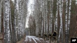 Oficerët e rojës kufitare ukrainase patrullojnë kufirin shtetëror Ukrainë-Bjellorusi në një pikë kontrolli në Novi Yarylovychi, Ukrainë, të hënën, 21 shkurt 2022