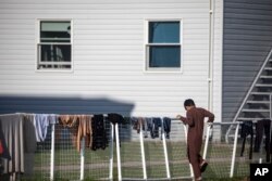 Seorang pengungsi Afghanistan berdiri di luar perumahan sementara di pangkalan Angkatan Darat AS Fort McCoy pada hari Kamis, 30 September 2021 di Fort McCoy, Wisconsin. (Foto: via AP)