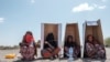 Pengungsi perempuan duduk di bawah kotak kardus bertuliskan Badan PBB urusan Pengungsi (UNHCR) saat mereka menunggu didaftarkan oleh pihak berwenang di kompleks Hotel Agda, kota Semera, wilayah Afar, Ethiopia, 14 Februari 2022. (EDUARDO SOTERAS / AFP)
