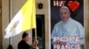 Seorang Pastor memegang bendera di dekat poster Paus Fransiskus, dalam persiapan menjelang kunjungan Paus di gereja Mar Youssif Church, Baghdad, Irak (26/2). 