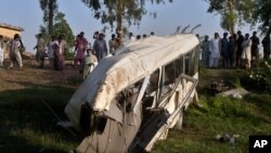 Penduduk setempat berkumpul di sekitar bus yang hancur akibat tabrakan dengan kereta api di Farooq Abad, distrik Sheikhupura, Pakistan, Jumat, 3 Juli 2020. 