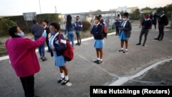 Seorang guru memeriksa suhu tubuh murid-muridnya sebelum masuk kelas di Langa, Cape Town, Afrika Selatan, 8 Juni 2020.