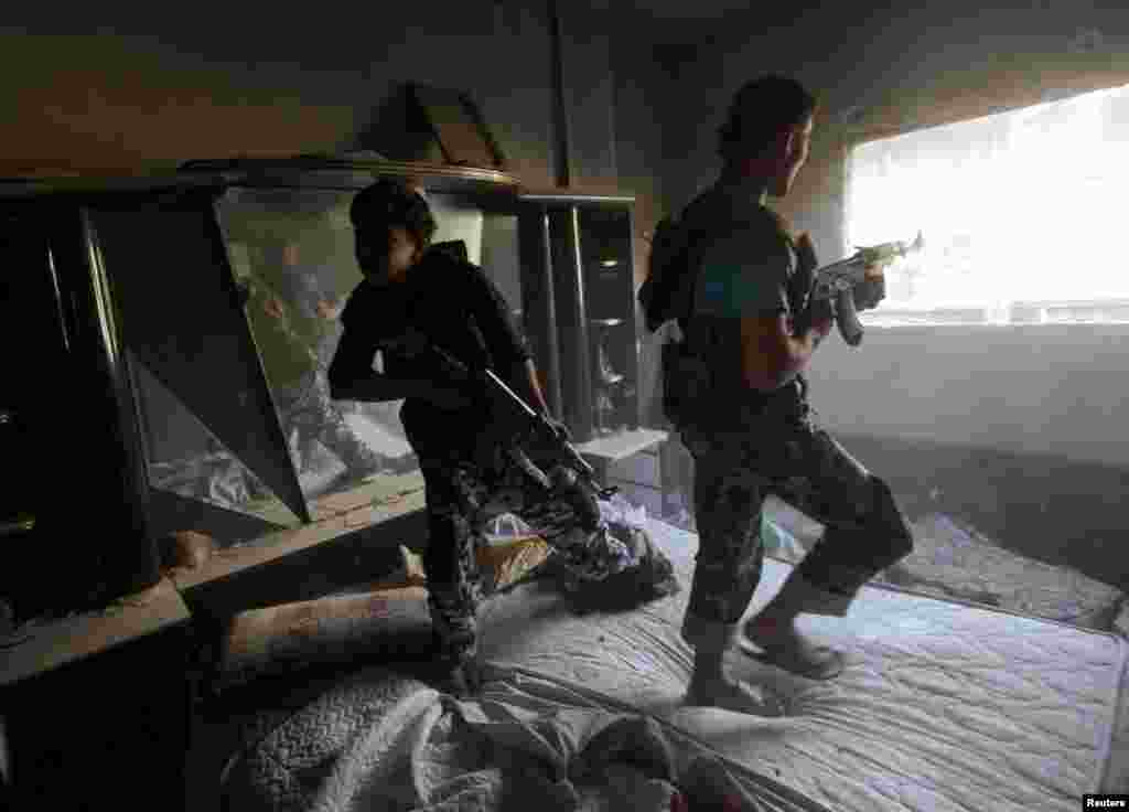 A Free Syrian Army fighter reacts as his fellow fighter aims his weapon during what activists said were clashes with forces loyal to Syria's President Bashar al-Assad in Deir al-Zor, Oct. 1, 2013.