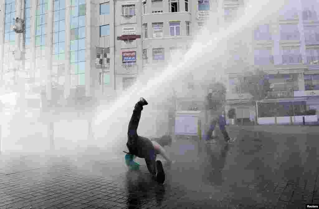 Seorang demonstran jatuh setelah terkena air dari meriam yang digunakan polisi huru-hara dalam protes anti-pemerintah di Alun-Alun Taksim, pusat kota Istanbul (31/5). (Reuters/Murad Sezer)