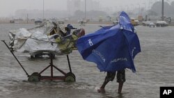 A boy struggles to hold onto his umbrella during strong winds on Marina beach in the southern Indian city of Chennai, December 29, 2011.