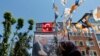 FILE - A woman walks past a poster with Turkey's Prime Minister Recep Tayyip Erdogan in the Kasimpasa neighborhood of Istanbul, where he was born, June 19, 2013.
