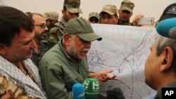 FILE - Iraqi militia leader Hadi al-Amiri of the Badr Brigades Shiite militia explains a battle plan to his fighters near the front line on the outskirts of Fallujah, Anbar province, Iraq, June 1, 2015. 