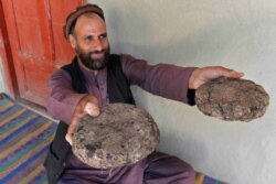 FILE - 37-year-old farmer Mohaiyudeen displays packages of opium after harvesting it from his poppy fields in the Surkh-Rod district of Nangarhar province, Afghanistan, June 28, 2020.