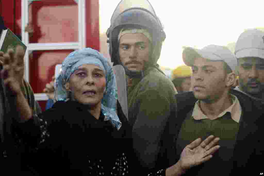 People gather at the scene of an explosion at a police headquarters building in the Nile Delta city of Mansoura, Egypt, Dec. 24, 2013.