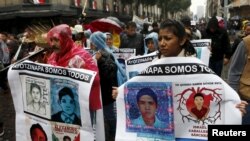 FILE - Relatives and friends hold banners with images of some of the 43 missing students of the Rural Normal School of Ayotzinapa as they march in Mexico City to mark the first anniversary of the students' disappearance, Sept. 26, 2015.