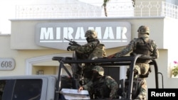 FILE - Military personnel stand atop a truck outside the Miramar building during a raid in Mazatlan.