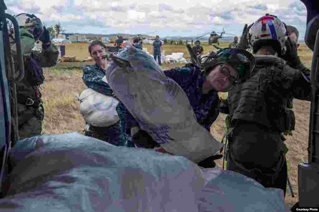 Aviation Electronics Technician 3rd Class Deanna Coutts, from Chicago, center, loads a bag of supplies into an MH-60S Seahawk from the "Golden Falcons" of Helicopter Sea Combat Squadron (HSC) 12 to be airlifted to nearby villages in support of Operation D