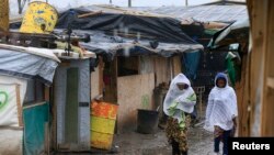 Des migrants marchent dans la boue dans la partie sud d'un camp des migrants appelé la «jungle» un jour d'hiver pluvieux à Calais, Nord de la France, 22 février 2016.