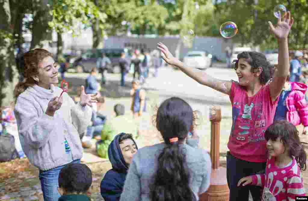 Children of migrants play with soap bubbles after arriving at a new emergency shelter in a sports hall near the Olympiastadion in Berlin, Germany.
