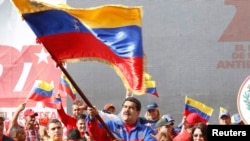 This Venezuelan government photo shows President Nicolas Maduro waving a flag to celebrate the anniversary of the "Caracazo" revolutionary uprising; in a speech at the rally, he announced the arrest of a U.S. pilot for alleged spying, Feb. 28, 2015.