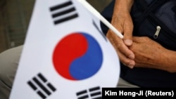 Seorang veteran perang Korea Selatan memegang bendera nasional dalam upacara memperingati 70 tahun Perang Korea, di dekat zona demiliterisasi yang memisahkan kedua Korea, di Cheorwon, Korea Selatan, 25 Juni 2020. (Foto: REUTERS/Kim Hong-Ji )