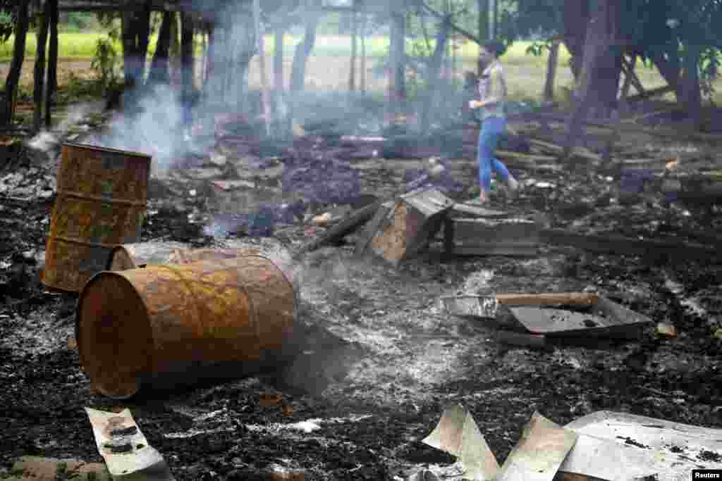 Seorang jurnalis berjalan di antara sisa-sisa bangunan yang dibakar di desa Shwe Lay, di luar daerah Thandwe di negara bagian Rakhine, Burma (2/10).