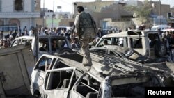 A Houthi fighter walks on a vehicle damaged by an air strike at a residential area near Sanaa Airport March 26, 2015. REUTERS/Khaled Abdullah 