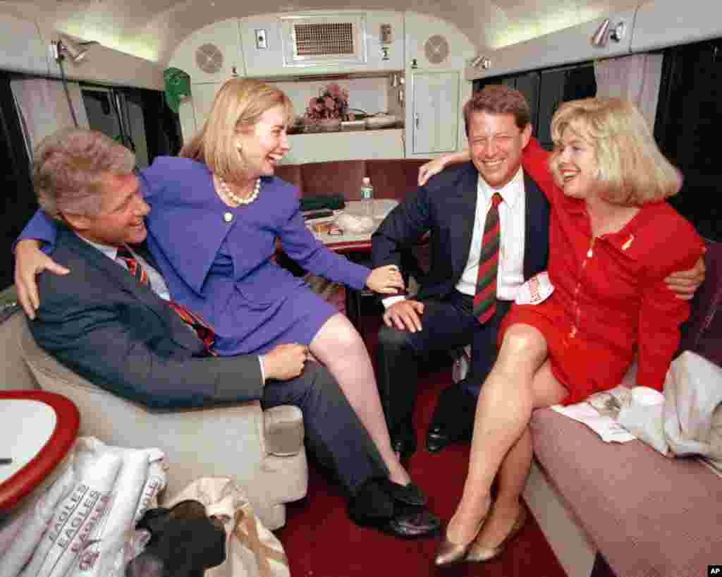 លោកស្រី Hillary Rodham Clinton អង្គុយនៅលើភ្លៅរបស់ស្វាមីលោកស្រី និងជាបេក្ខជនប្រធានាធិបតីគណបក្សប្រជាធិបតេយ្យលោក Bill Clinton ខណៈដែលលោកស្រីនិយាយកំប្លែងលេងជាមួយនឹងបេក្ខជនអនុប្រធានាធិបតីលោក Al Gore និងភរិយារបស់លោក គឺលោកស្រី Tipper អំឡុងពេលឈប់សម្រាកខ្លីមួយតាមរថយន្តក្រុងក្នុងក្រុង Durham រដ្ឋ North Carolina កាលពីថ្ងៃទី២៦ ខែតុលា ឆ្នាំ១៩៩២។