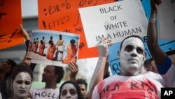 African migrants hold signs during a protest in front of the Rwandan embassy in Herzeliya, Wednesday, Feb. 7, 2018. On April 2, Israel announced a deal to resettle African migrants in Israel and the West, but backtracked on it hours later. (AP Photo/Ariel Schalit)