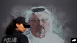 Polisi Turki berjalan di depan gambar Jamal Khasoggi, dekat kedutaan Arab Saudi di Istanbul, menjelang peringatan setahun meninggalnya jurnalis Washington Post itu, Oktober 2018. (Foto: dok).