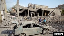 FILE - People stand at the site of a Saudi-led air strike in the Red Sea port city of Houdieda, Yemen, Sept. 5, 2016. 