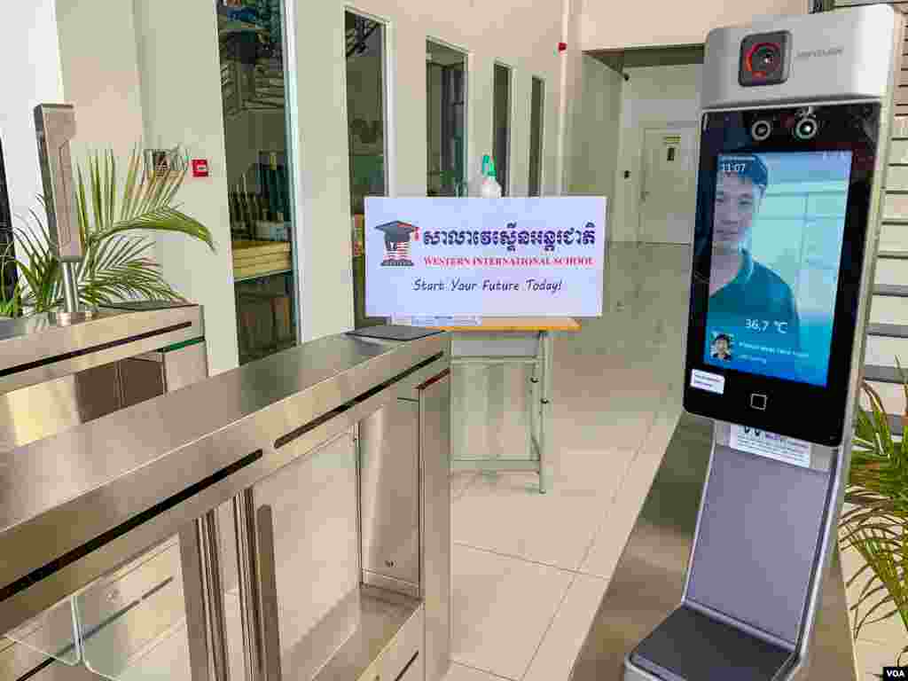ម៉ាស៊ីនវាស់កំដៅទំនើបដែលមានទ្វារ ត្រូវបានដាក់ប្រើប្រាស់នៅសាលាវេស្ទើនអន្តរជាតិ។ បើសិនជាអ្នកឆ្លងកាត់ មានកំដៅលើសពី ៣៧,៥ អង្សារសេ ទ្វារមិនបើកឲ្យចូលទេ។ ម៉ាស៊ីននេះប្រើសម្រាប់សិស្ស បុគ្គលិកទាំងអស់នៅក្នុងសាលាវេស្ទើនអន្តរជាតិ មុនចូលទៅក្នុងសាលា ទីក្រុងភ្នំពេញ ថ្ងៃទី៨ ខែកក្កដា ឆ្នាំ២០២០។ (ធីតា វីន/វីអូអេ)