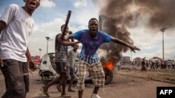 FILE - Demonstrators gather in front of a burning car during an opposition rally in Kinshasa, DRC, Sept. 19, 2016.