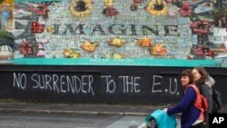 Pejalan kali berjalan melewati grafiti pro-Brexit di West Belfast, Irlandia Utara, 14 Oktober 2019. 