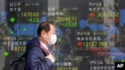 A man walks by an electronic stock board of a securities firm in Tokyo, Jan. 20, 2021.