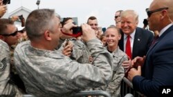 President Donald Trump poses for photographs while greeting members of the military on the tarmac upon his arrival on Air Force One at Francis S. Gabreski Airport in Westhampton, New York, Aug. 17, 2018.