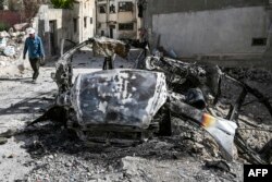 Seorang pria Palestina berjalan melewati kendaraan yang hancur di Jenin setelah serangan pasukan Israel di kota Tepi Barat yang diduduki pada 23 Mei 2024. (Foto: AFP)