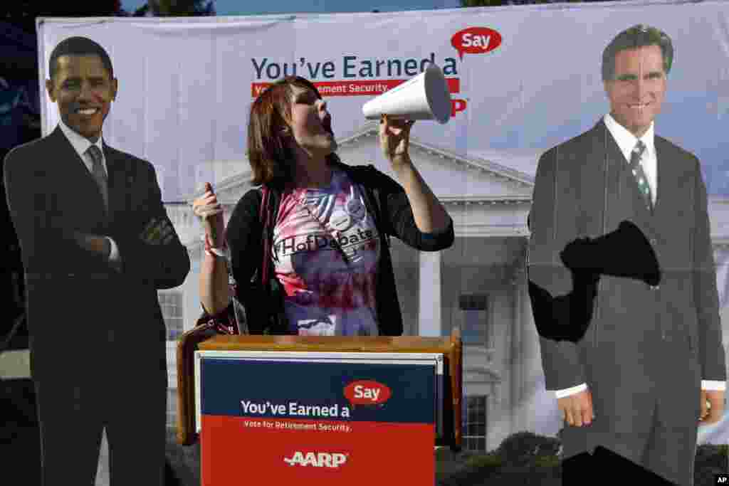 Mahasiswi Universitas Hofstra Corinne Mestemacher berpose dengan pengeras suara di depan patung Presiden Barack Obama dan kandidat Partai Republik Mitt Romney.