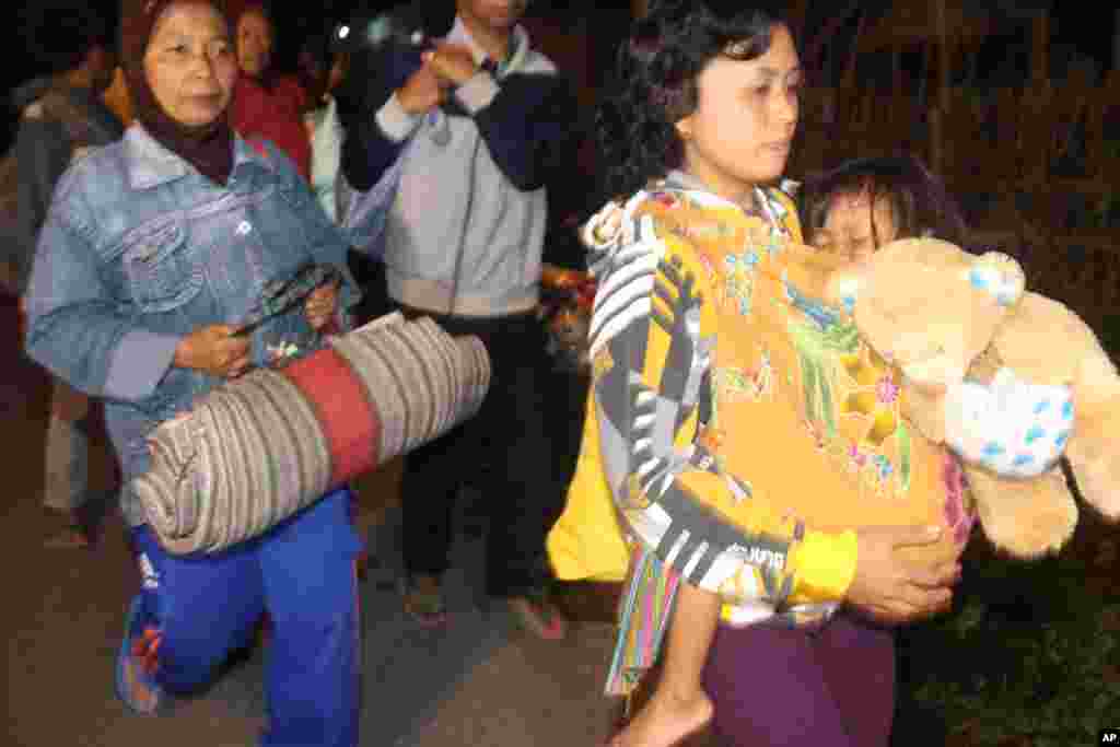 Dua warga desa mengungsi dari rumah-rumah mereka di Kediri, Jawa Timur, Kamis (13/2). 
