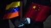 FILE - Venezuelan Foreign Minister Jorge Arreaza, wearing protective gloves as a preventive measure against the spread of COVID-19, holds Venezuelan and Chinese flags at the Simon Bolivar International Airport in La Guaira, Venezuela, on March 30, 2020.