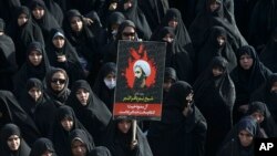 Seorang perempuan Iran di Teheran, Iran, mengacungkan poster Sheikh Nimr al-Nimr, seorang ulama Syiah terkenal yang dieksekusi oleh Arab Saudi, 4 Januari 2016.
