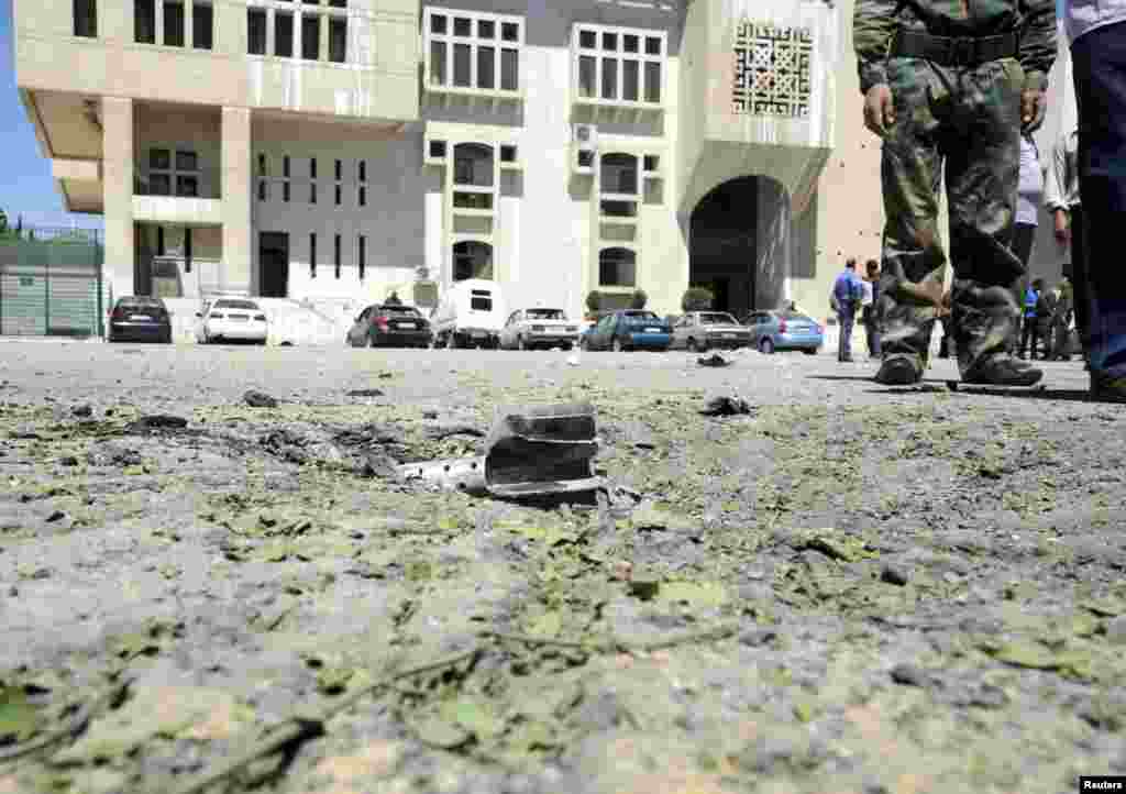 A mortar shell is seen in front of vehicles after mortars landed on two areas in Damascus, April 29, 2014. (SANA)