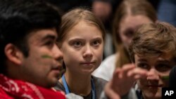 Climate activist Greta Thunberg, center, talks with other climate activists youth at the COP25 climate talks summit in Madrid, Dec. 6, 2019. 