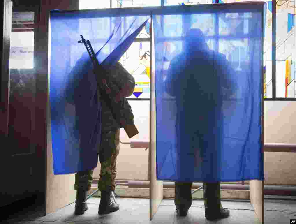 Pro-Russian rebels cast their ballots at a polling station inside a rebel military base during elections held by pro-Russian separatists, Donetsk, eastern Ukraine, Nov. 2, 2014. 