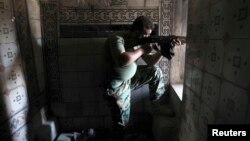 A Free Syrian Army fighter aims his weapon as he takes position inside a house in the city of Aleppo July 11, 2013. 