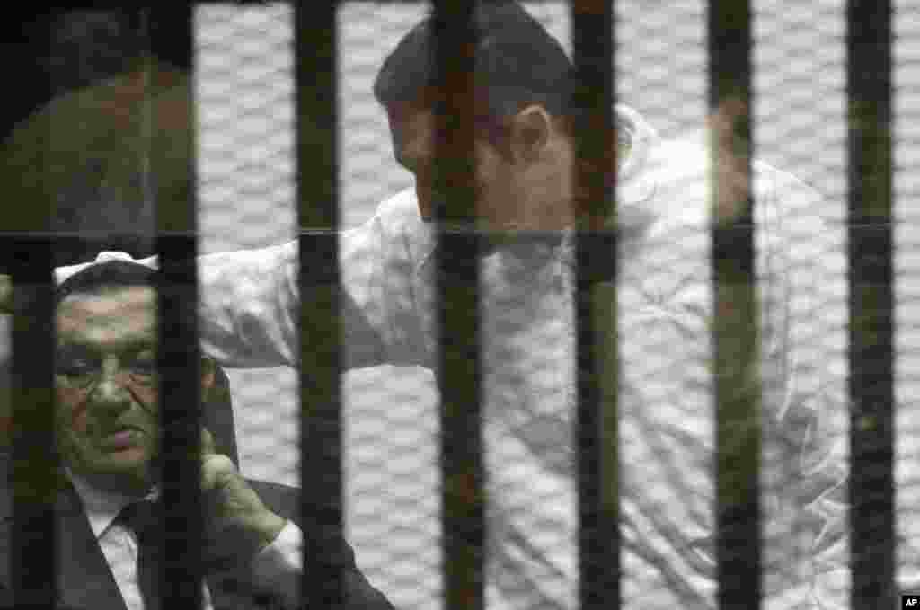Presiden Mesir terguling Hosni Mubarak duduk di ruangan terdakwa dengan gelar protektif bersama anaknya Alaa (kanan) dalam sidang pengadilan di Kairo, 21 Mei 2014.