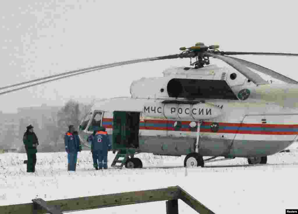 Russian emergency ministry personnel stand near a helicopter at a field next to the Penal Colony 7, where Mikhail Khodorkovsky was incarcerated near the Finnish border, 300 km south of the Arctic Circle, Dec. 20, 2013.