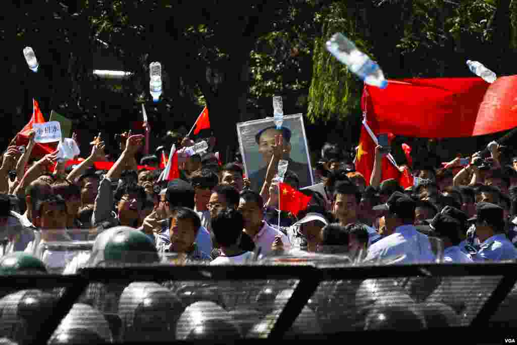 Anti-Japan protesters throw water bottles towards the Japanese Embassy while marching on a street outside the embassy, Beijing, China, September 18, 2012.