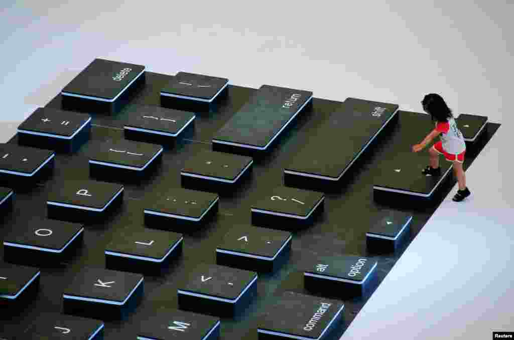 A child climbs onto a giant mockup laptop keyboard during a promotion event at a shopping center in Beijing, China.