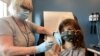 USA, North Carolina, Bridgette Melo, 5, prepares for her inoculation of one of two reduced 10 ug doses of the Pfizer BioNtech COVID-19 vaccine during a trial 