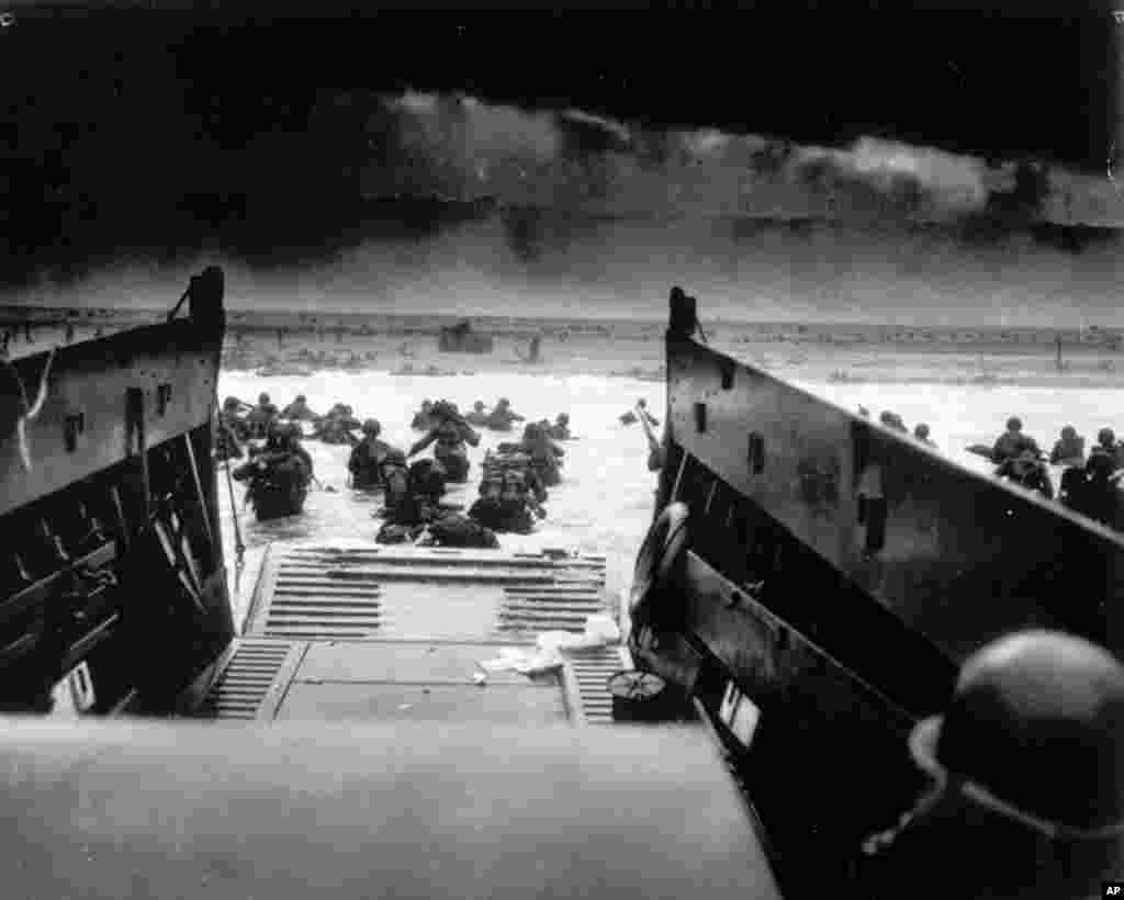 Saat diserang dengan tembakan senapan mesin dari penjaga pertahanan maritim Jerman, tentara Amerika turun dari kapal penjaga pantai AS dalam operasi pendaratan Sekutu di Normandia, Perancis,&nbsp;6 Juni 1944.
